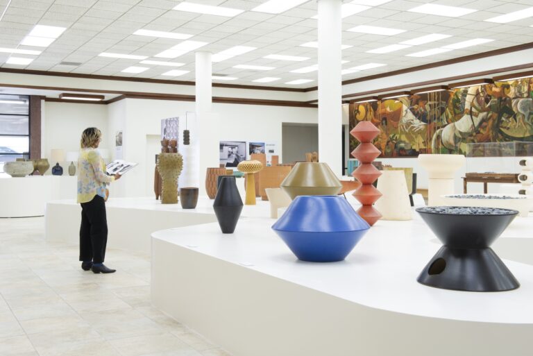 Exhibition view of "Architectural Pottery: Ceramics for a Modern Landscape" with museum guest holding accompanying book. Photo credit: Dan Chavkin