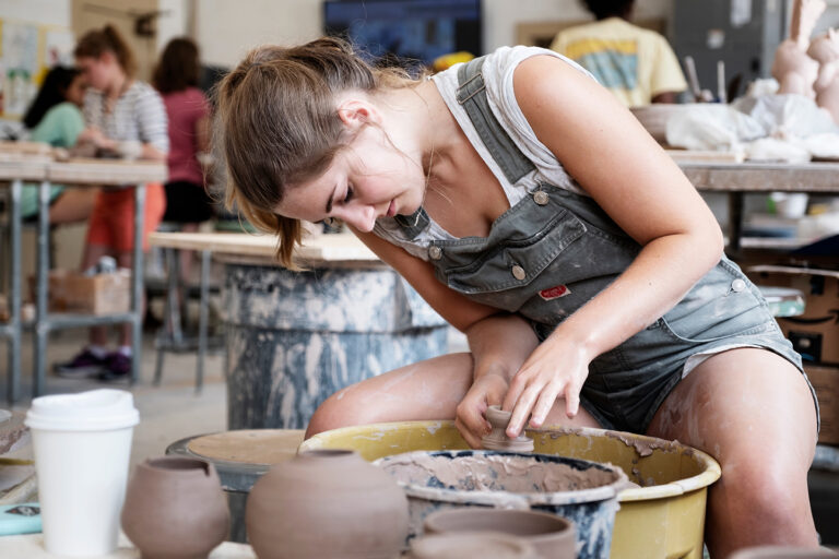 Art students working in the Howell Hall ceramics with studio: Laura Leigh Hicks in overalls (graphic design student). (photo by Megan Bean / © Mississippi State University)