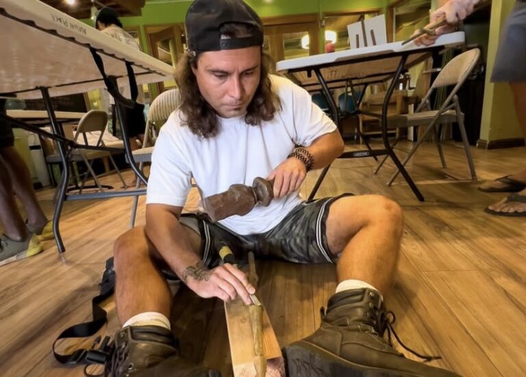 Paumalu Cassidy carving a fishing spear in Anthony Watsonʻs carving workshop