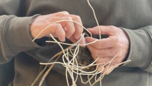 An artist weaves a basket from harvested invasive vines during Angela Eastman's workshop retreat in the Antinori Village. Hambidge Staff