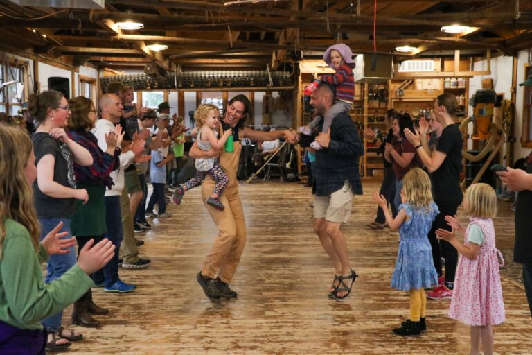 Adults and children enjoy a traditional contra dance in the Red Building (a timber framed woodshop) during North House’s annual Summer Solstice and Wooden Boat Festival, one of a number of free community events throughout the year. North House Folk School