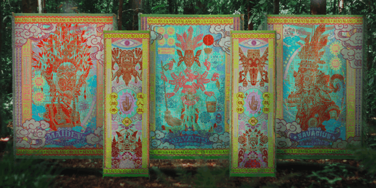 Five colorful tapestries hang in a row. They are intricately woven and suspended in a forest with green and brown foliage in the background and foreground. Marcos Kueh, Kenyalang Circus: Exotic Workers Series, 2023. Industrial woven recycled PET, dimensions vary. From the Surface Design Journal's Summer 2025 Issue, Modern Weavers/New Spirit