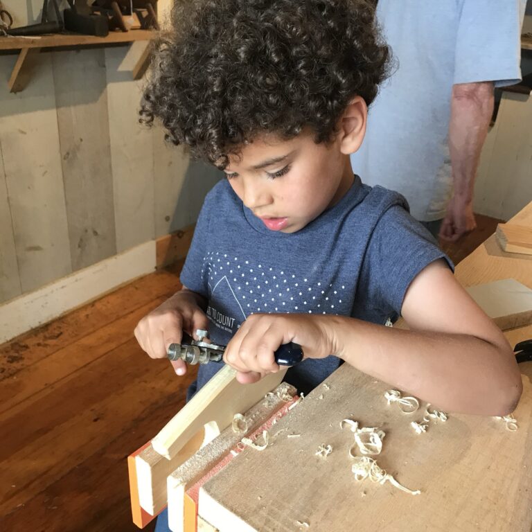 A young visitors learns how to shape wood with a hand plane during Hands-On History activities at the Wilson Museum A young visitors learns how to shape wood with a hand plane during Hands-On History activities at the Wilson Museum. Wilson Museum Staff