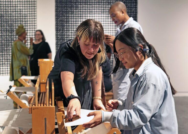 A visitor learns how to weave on a loom in the exhibition, “Sonya Clark: We Are Each Other” at Houston Center for Contemporary Craft. Photo by Kerrisa Treanor. A visitor learns how to weave on a loom in the exhibition, “Sonya Clark: We Are Each Other” at Houston Center for Contemporary Craft. Photo by Kerrisa Treanor.