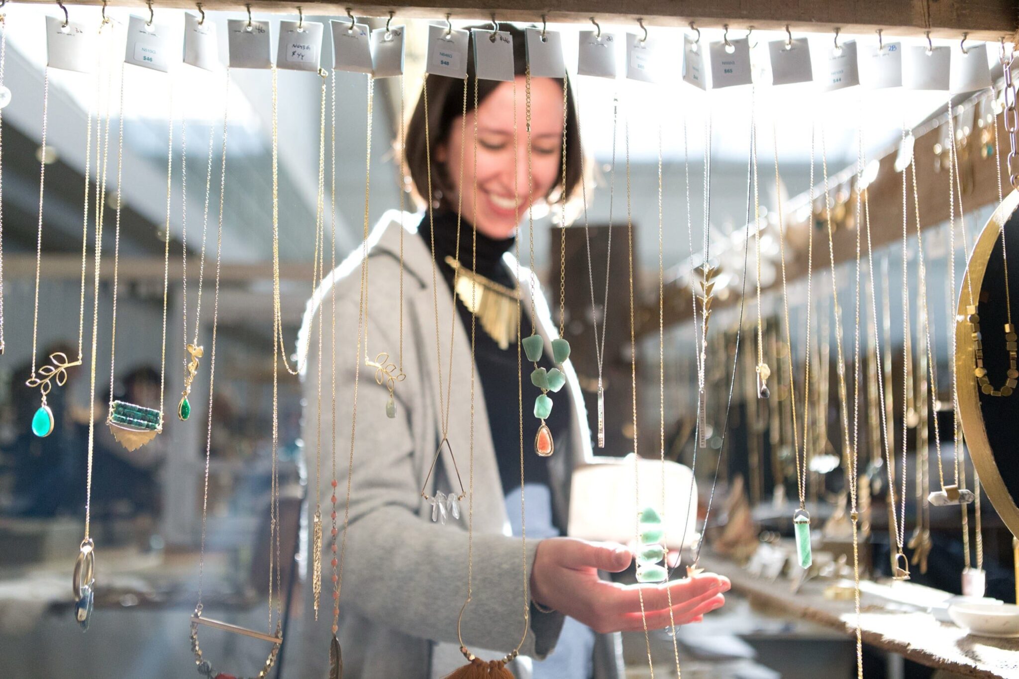 Shopper admiring jewelry at Handmade Arcade's 2018 Holiday Market. Photo Credit: Joey Kennedy, courtesy of Handmade Arcade