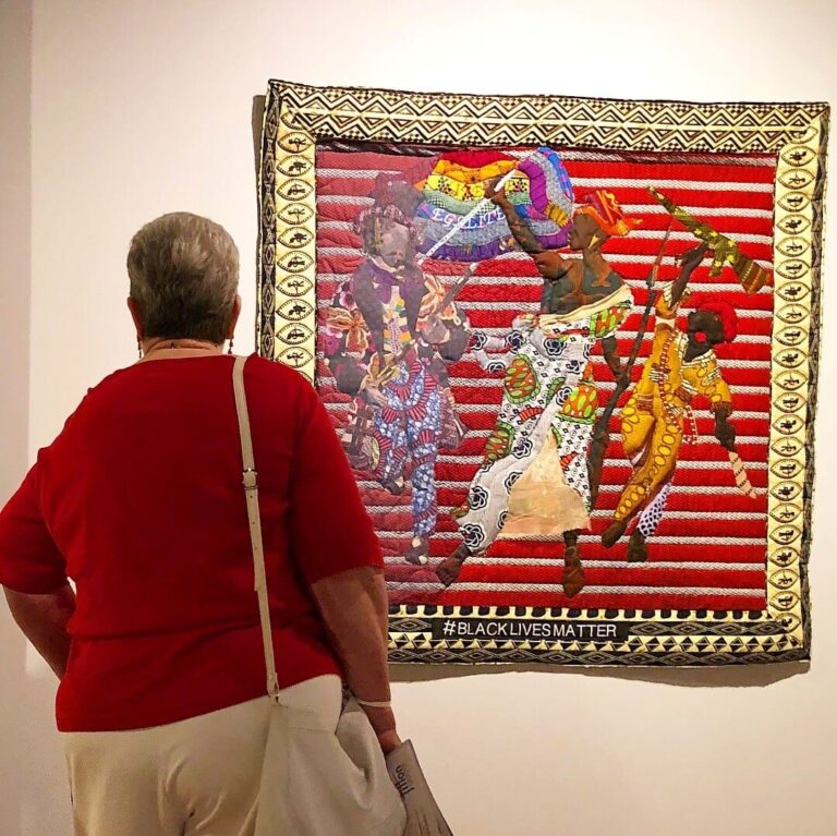 A visitor engages with “Black Lives Matter,” by Deanna Tyson, part of “Visioning Human Rights in the New Millennium: Quilting the World’s Conscience,” organized by Carolyn Mazloomi, featuring the Women of Color Quilters Network and Friends, presented by the Fitton Center for Creative Arts, summer 2018. Courtesy of Fitton Center for Creative Arts