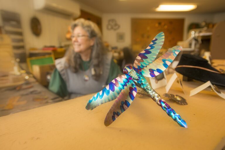 Copper Colorist Racheal Mathews in her shop at the Ozark Folk Center State Park with one of her flame painted dragonflies. Kirk Jordan