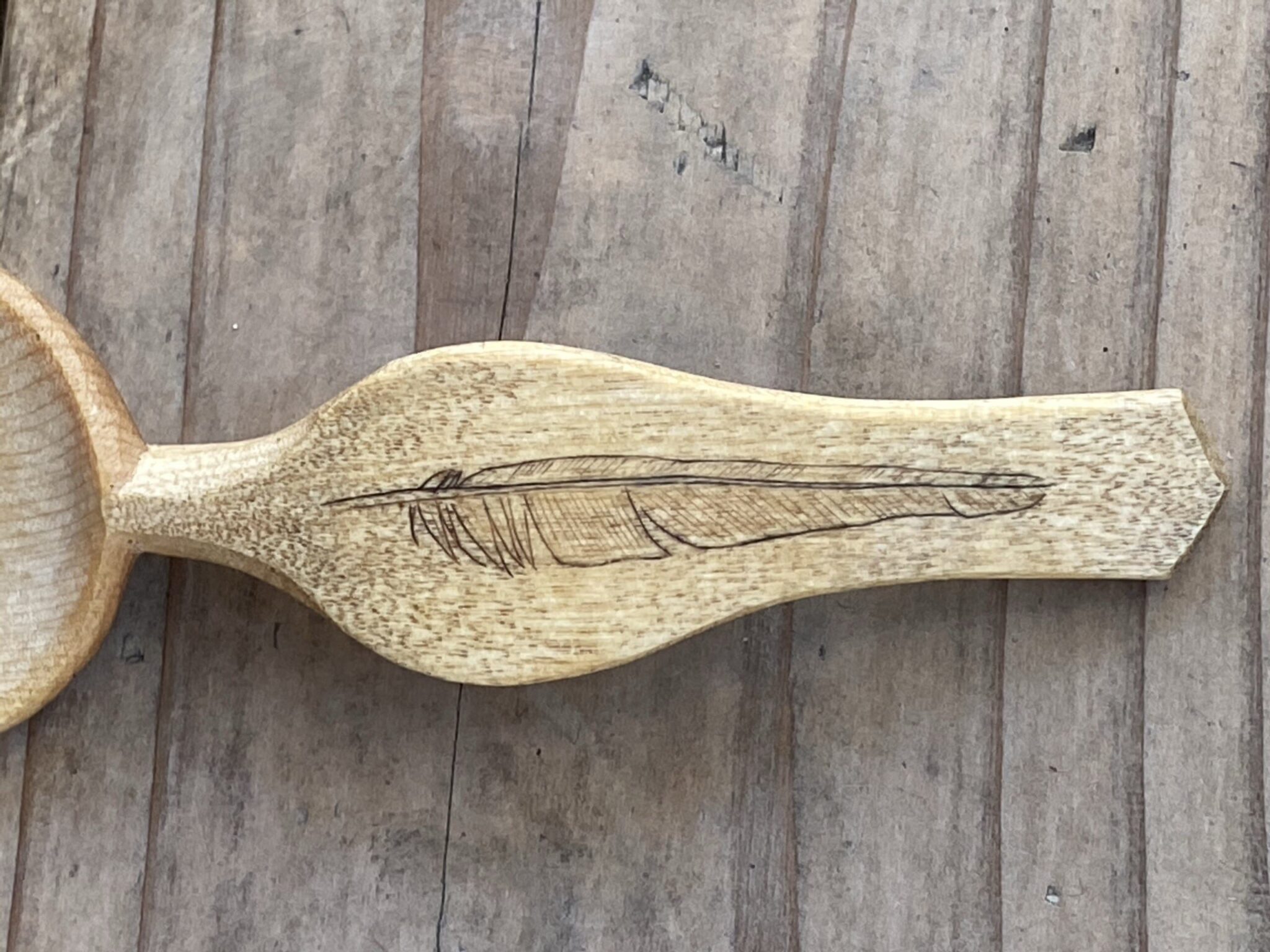 Spoon handle with the image of a feather carved into the handle. American Swedish Institute