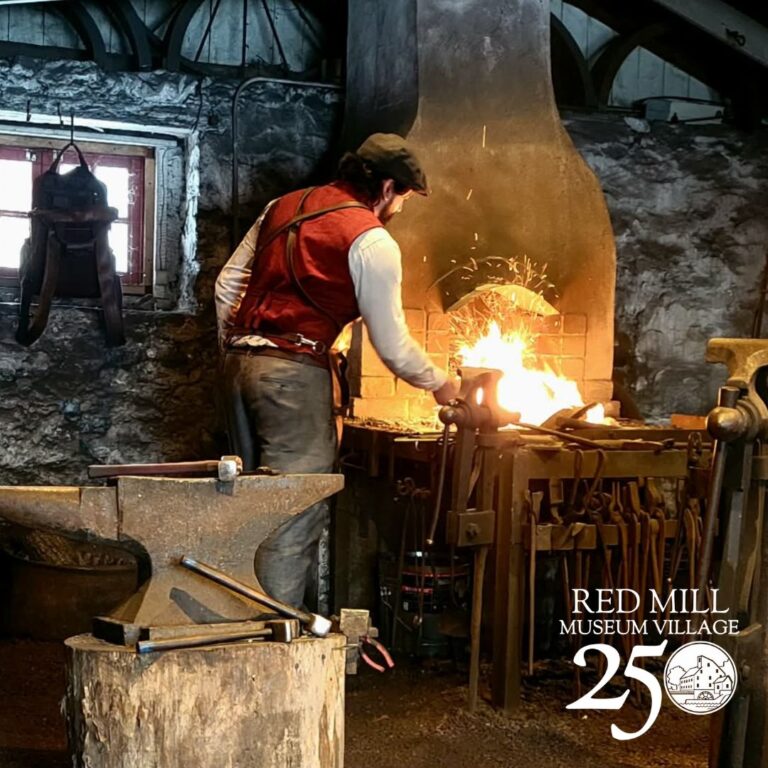 Red Mill Education Team Member demonstrating blacksmithing. Red Mill Museum Village Red Mill Education Team Member demonstrating blacksmithing. Red Mill Museum Village