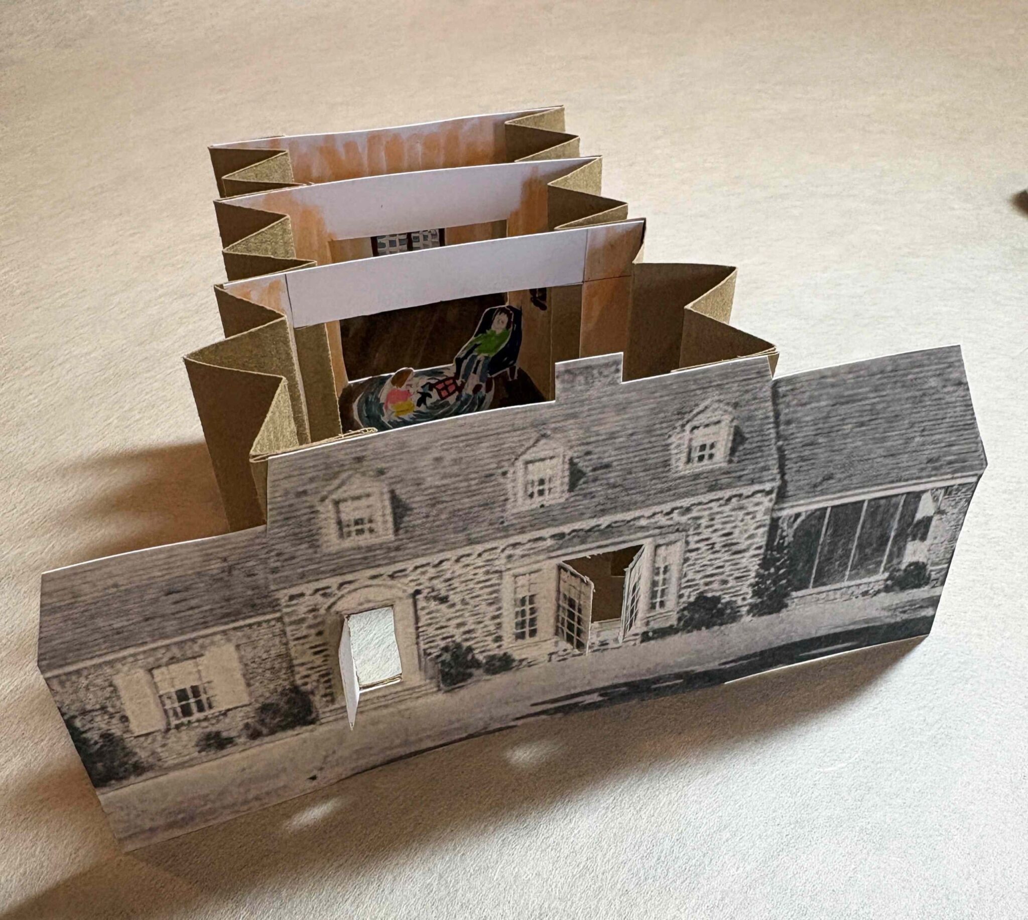 Expanded tunnel book, its cover is a black and white image of a house with open doors and windows. RCW Paper Museum