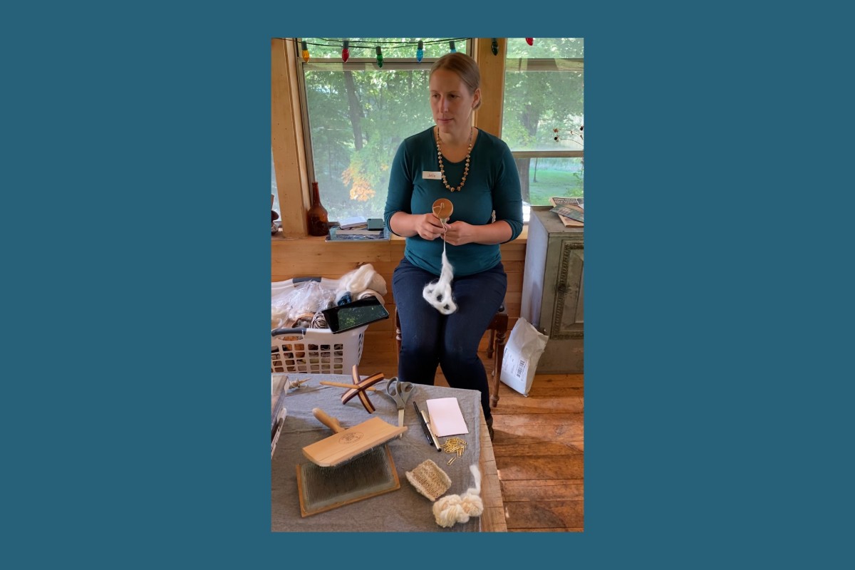 A woman demonstrating how to use a drop spindle with fiber. American Swedish Institute