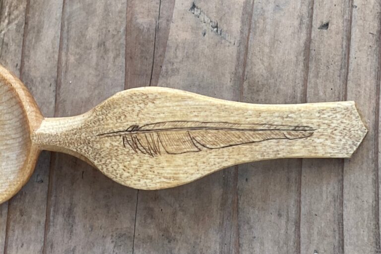 Carved wooden spoon with feather design on handle. American Swedish Institute