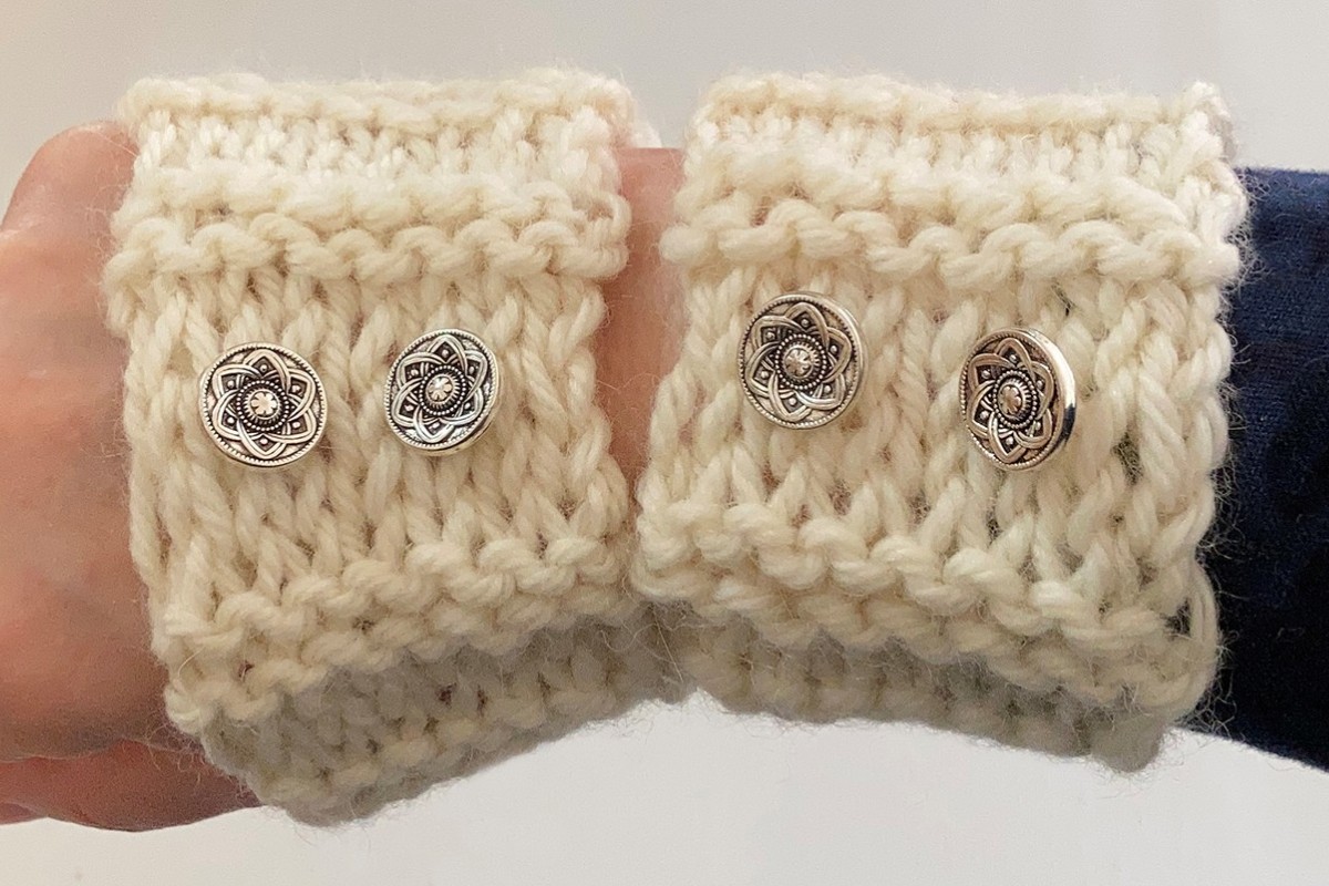 Close-up of knitted wrist warmers with decorative buttons. American Swedish Institute