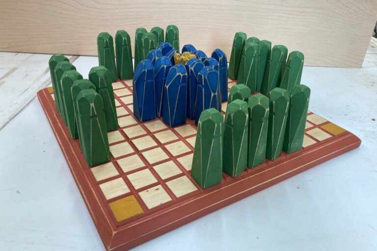 A board game with green and blue pieces is set up. American Swedish Institute