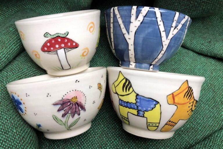 Four white bowls with painted nature designs. American Swedish Institute