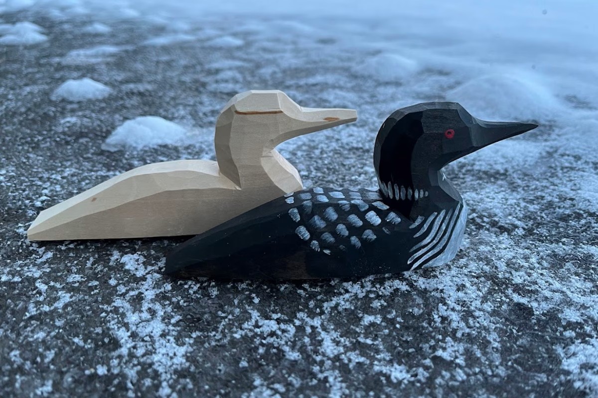 Two small loons carved out of wood one is pained and the other is plain wood. American Swedish Institute