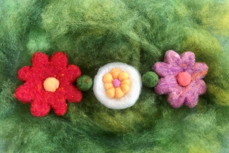 Three felt flowers on a green background. American Swedish Institute
