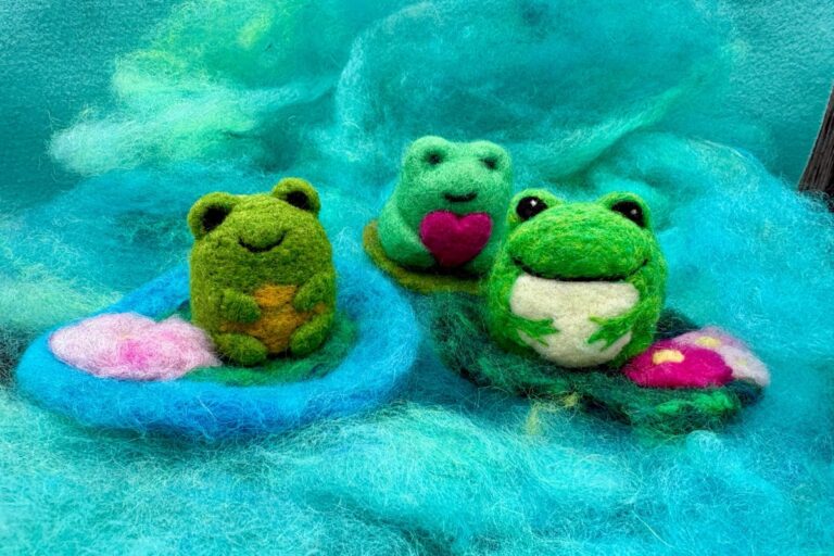 Three small felted frogs sitting on lily pads. American Swedish Institute