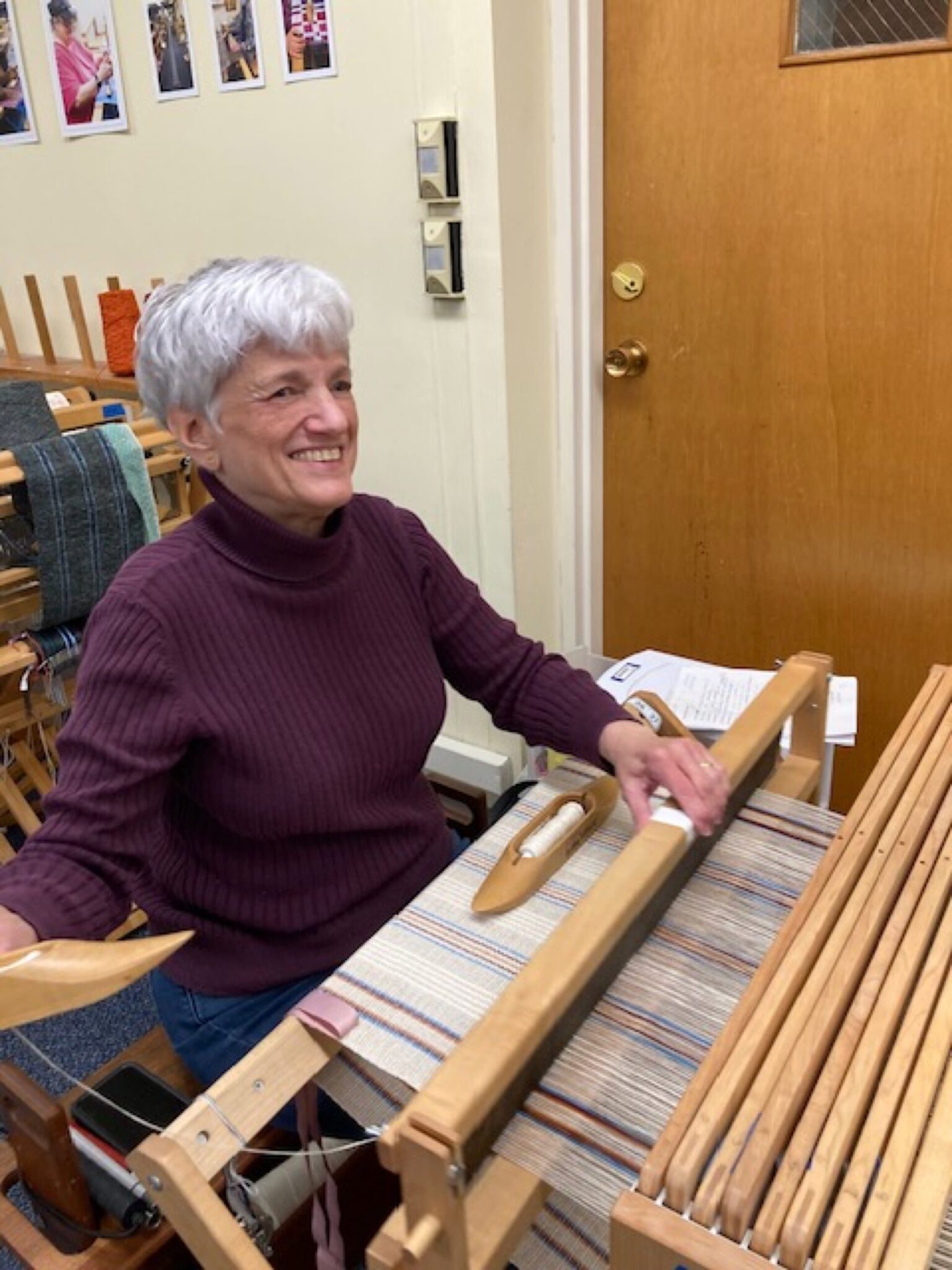 Artisan Joanna is seated at her loom weaving fabric for a series of towel. Hartford Artisans Weaving Center