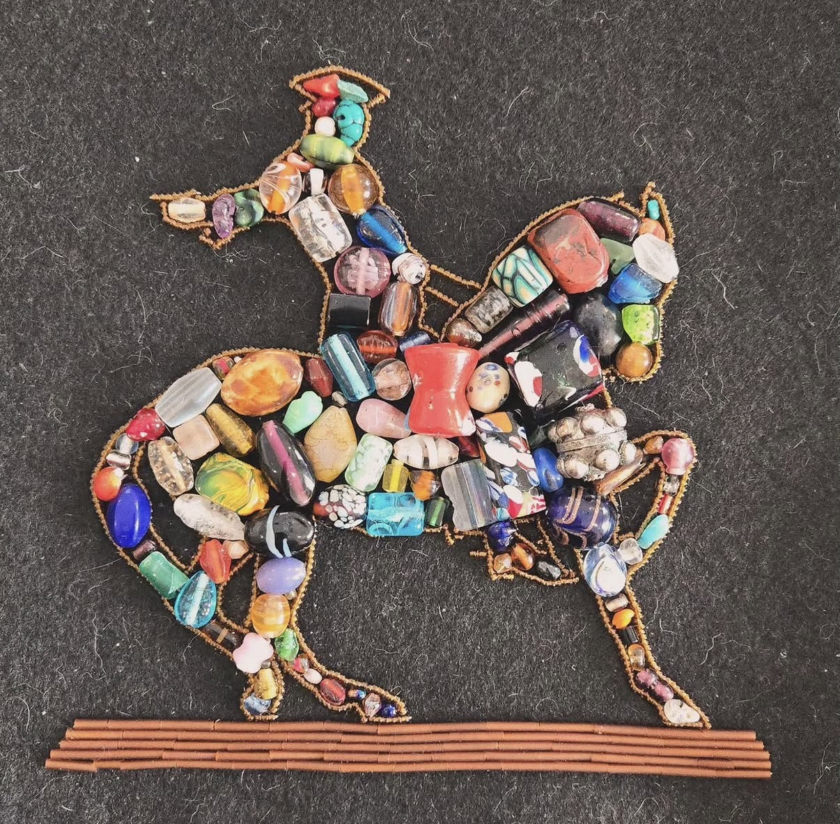 Colorful beads of all shapes and sizes fill out the shape of the famous statute of Paul Revere on a horse, in 2-D. Sage Carbone