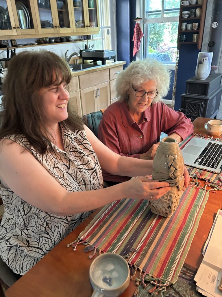 Cheryl smiles as she explores Pat Halles braided clay vessel. Pat sits to her rightl Cheryl smiles as she explores Pat Halles braided clay vessel. Pat sits to her rightl. Kade Sawyer