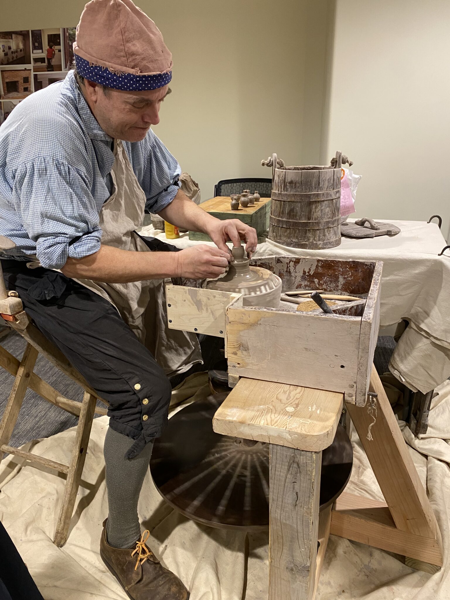 Potter dressed in 18th century style clothing works at a wheel. Paul Revere House