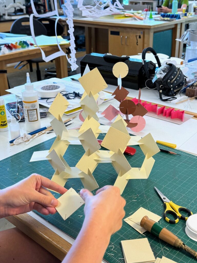 A pair of hands assembles a paper sculpture. A pair of hands assembles a paper sculpture. Michael Velliquette