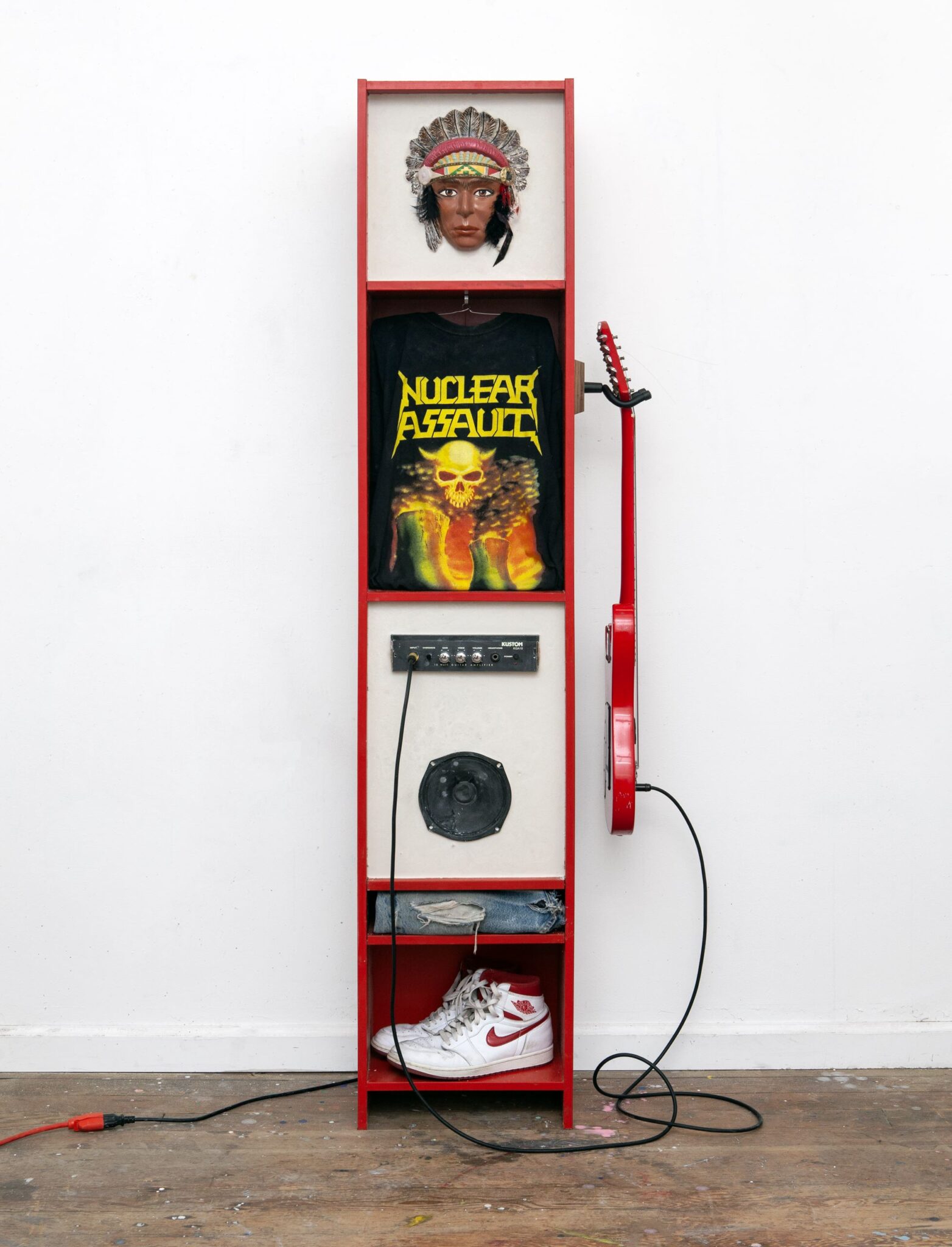 Justin Guthrie, "Rez Metal Spirit Cabinet," 2025 Modified found cabinet, functional Kustom guitar amp, vintage metal t shirt, ceramic chief mask, Memphis electric guitar, Nike Jordan 1s, ripped Levi’s and poured plaster. Courtesy of the Artist